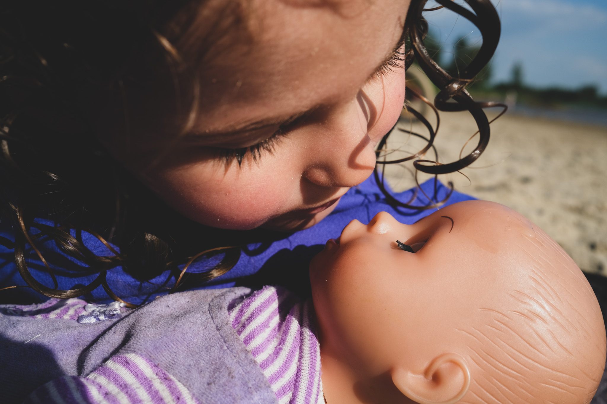 dziecko daje buziaka lalce, zdjęcie kolorowe w dużym zbliżeniu, plaża nad Wisłą, warszawa